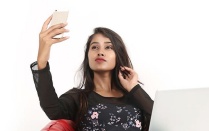 young woman views her smartphone while sitting comfortably. 