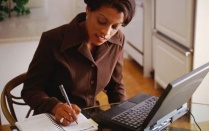 Woman taking notes while working on her laptop.