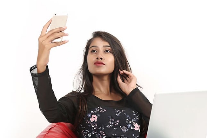 young woman views her smartphone while sitting comfortably. 